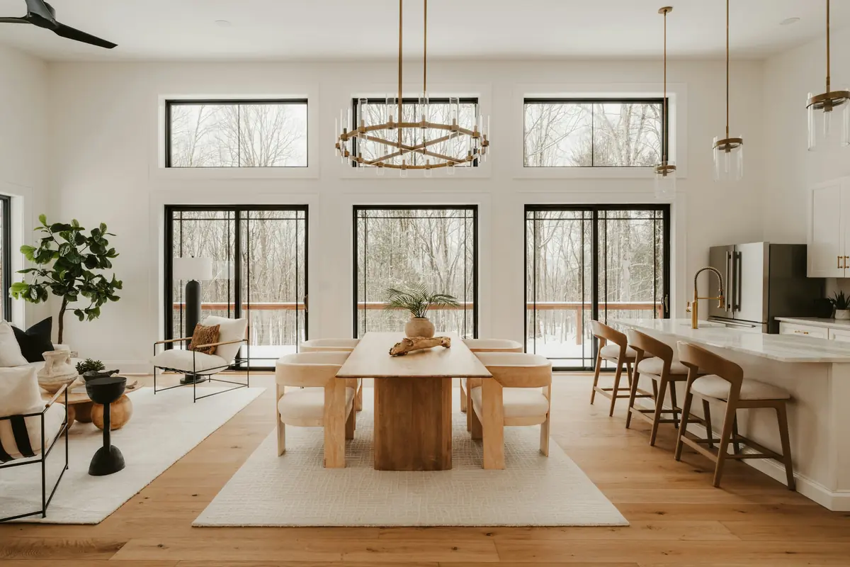 Open-plan living, dining and kitchen space with tall black-framed windows, oak floors and brass chandelier